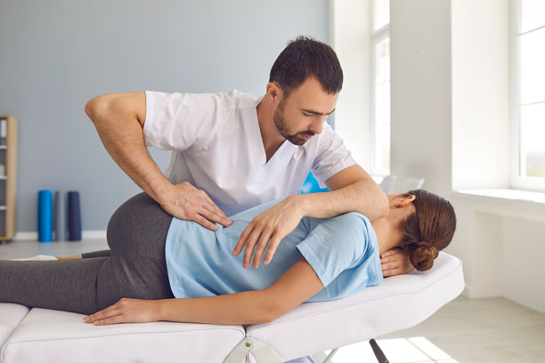 A chiropractor adjusting a patient's hips.