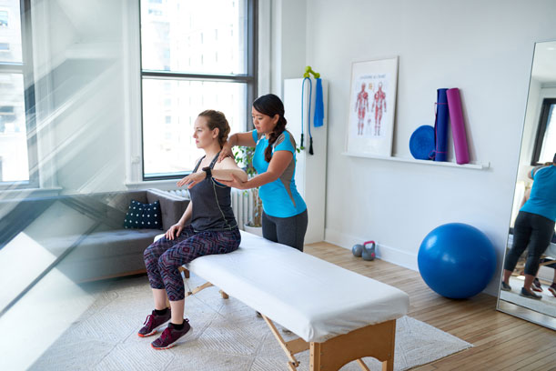 A woman works with a physiotherapist at a physiotherapy session in a clinic.